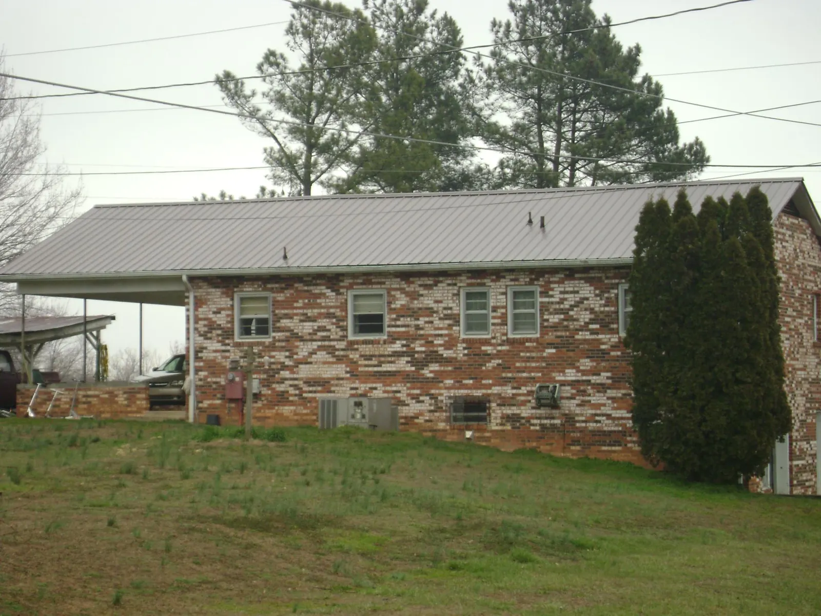 Gray metal roof on a brick split level home with a carport in Englewood