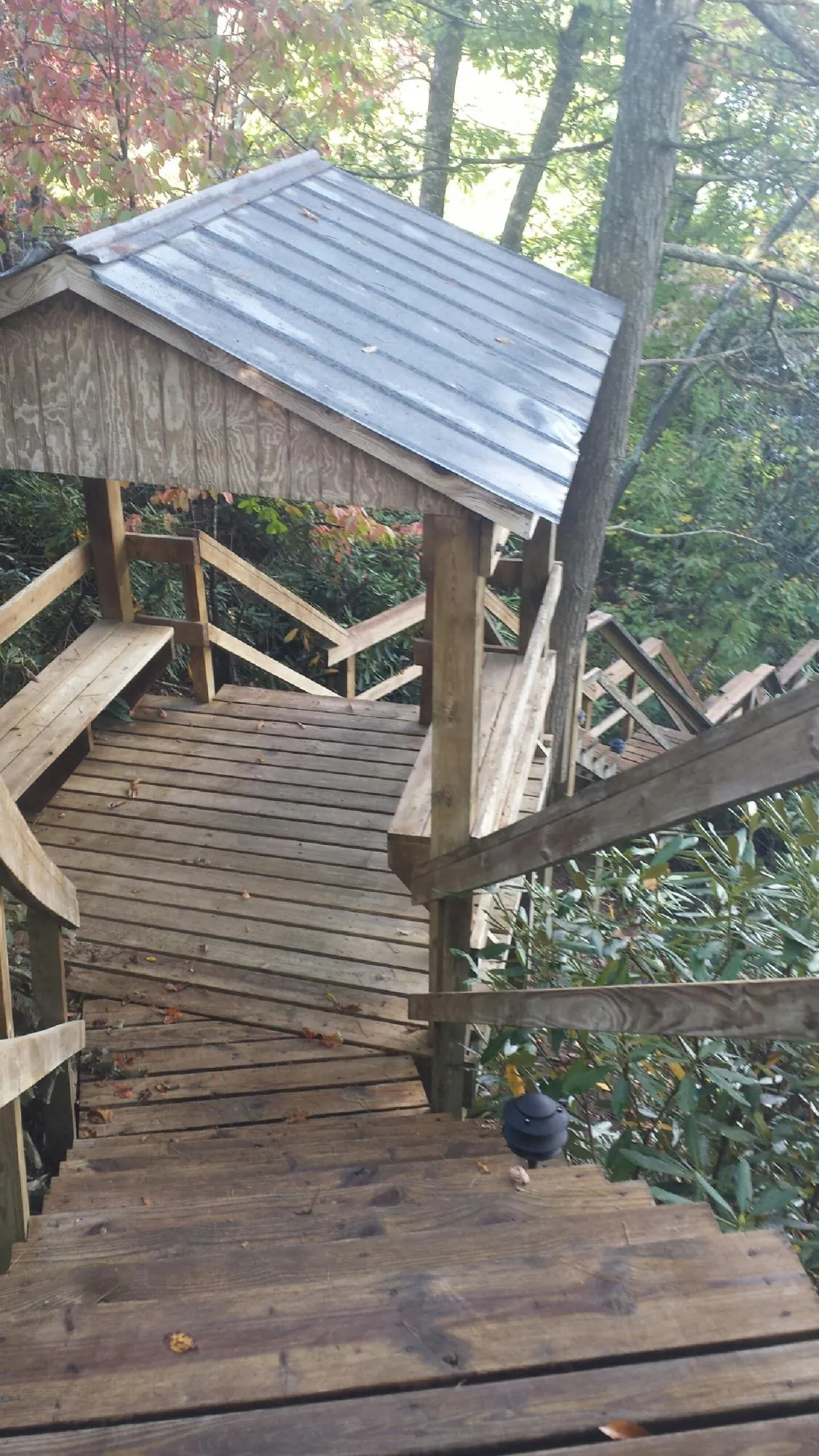Metal roofed shelter over wooden steps on a wooded walkway — Skylight Repair & Installation work by our crew in Englewood